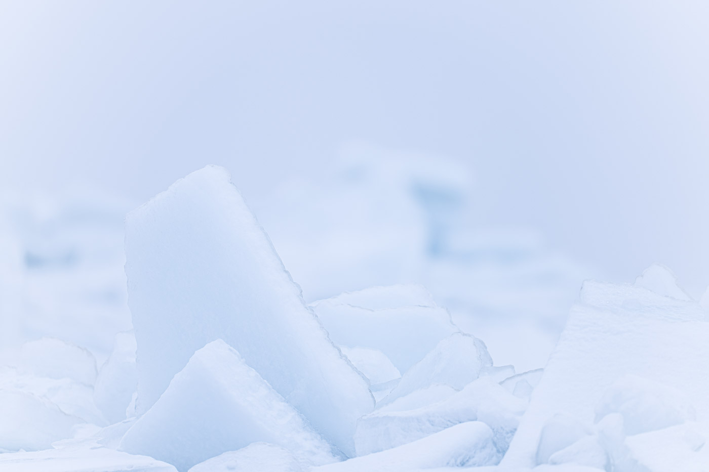 Eisspitzen im Vordergrund mit unscharfem Leuchtturm von Sassnitz dahinter.