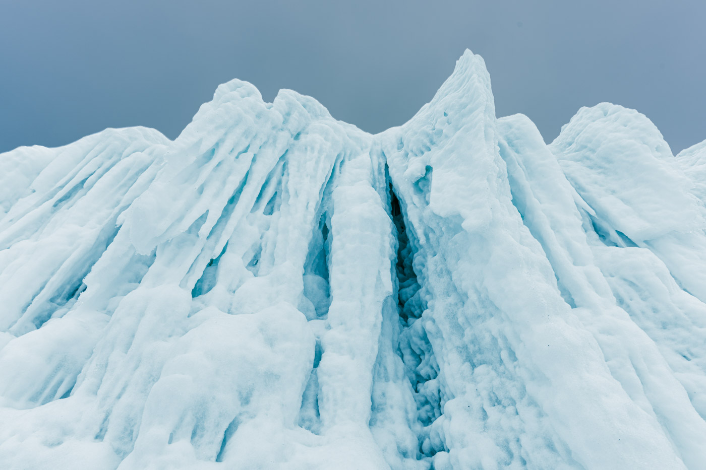 Spitze Eisformationen mit weißen Kanten und türkisblauen Vertiefungen.